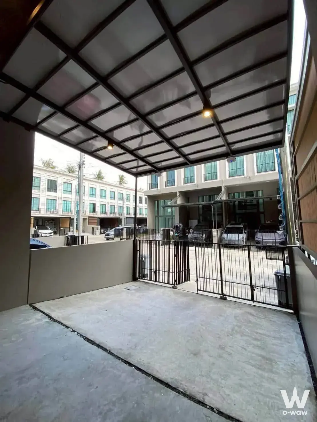 Covered carport with black metal gate and translucent roof panels at Patio Kalapapruek-Sathorn townhouse