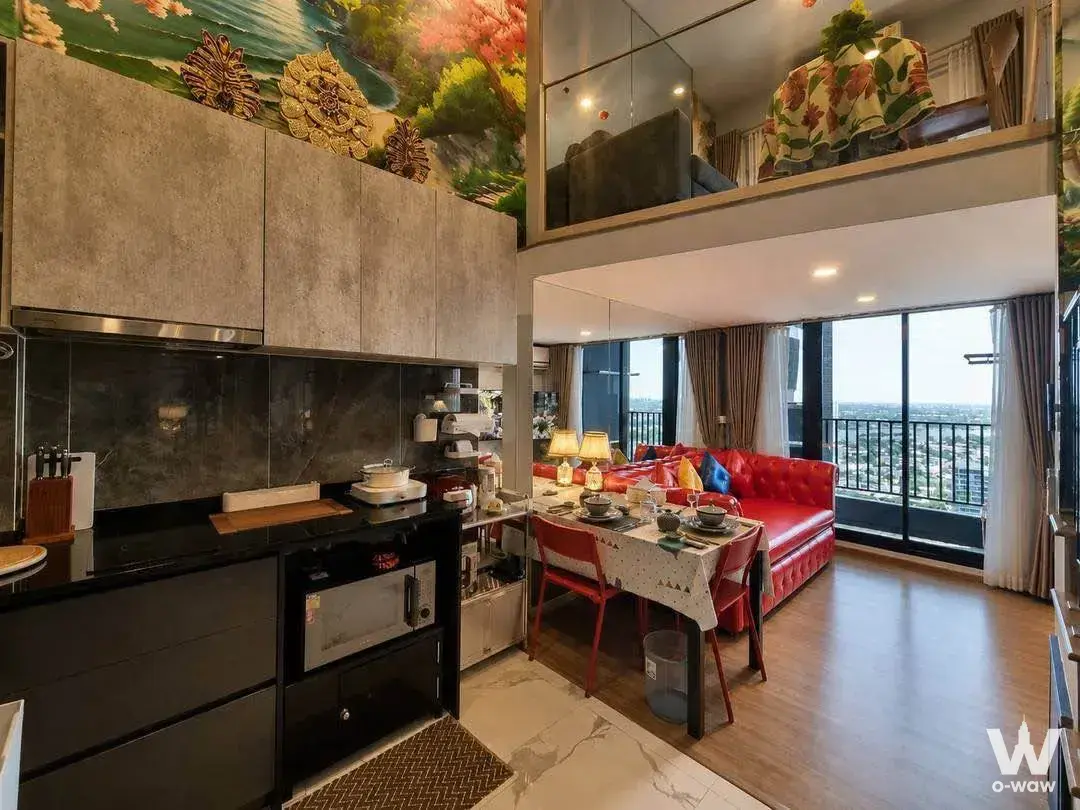 Open-plan loft kitchen and living area with red sofa and mezzanine in Ken Attitude Rattanathibet condo