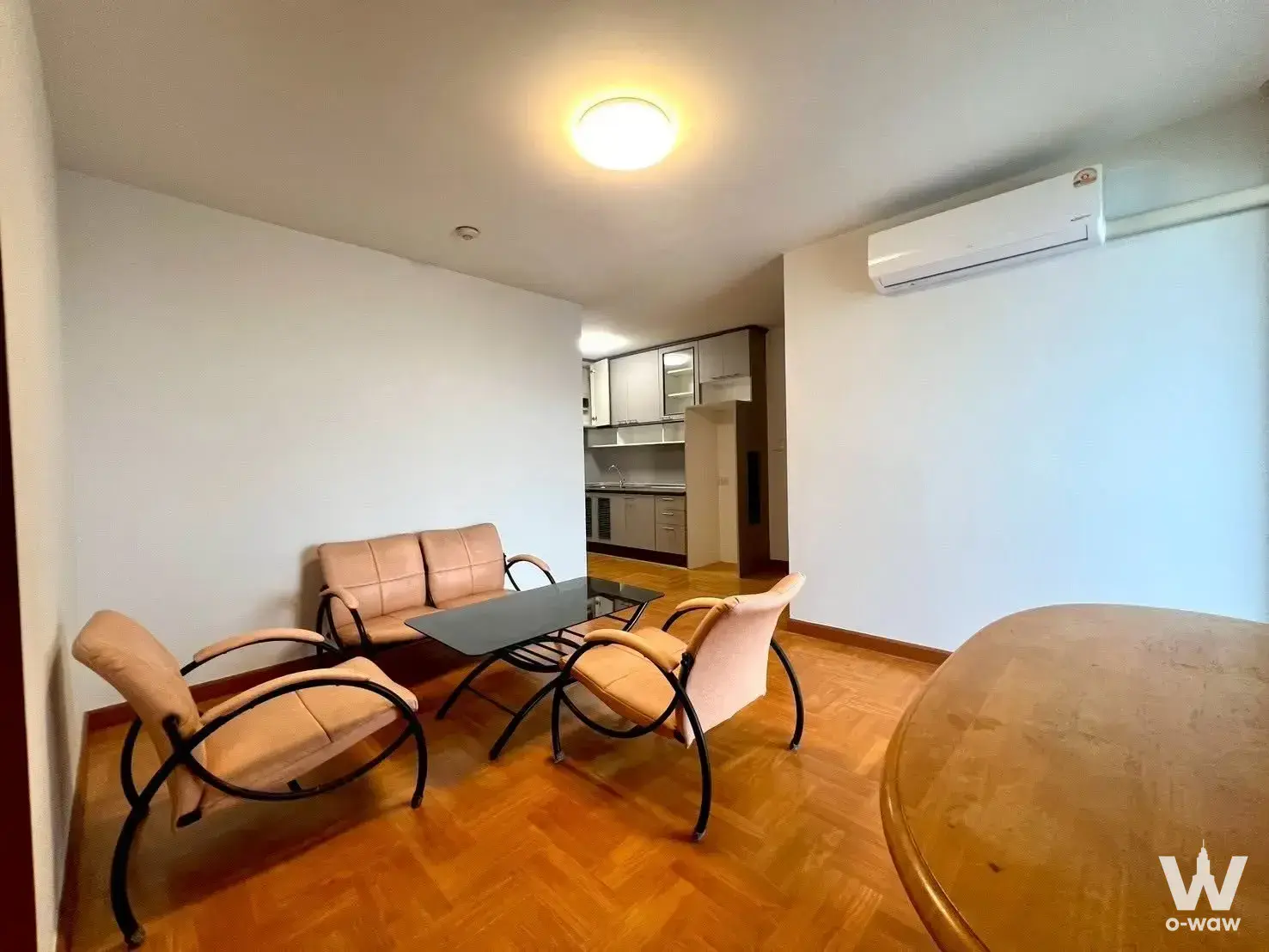 Ratchada Pavilion living room with honey parquet floors, tan leather sofa, and open kitchen