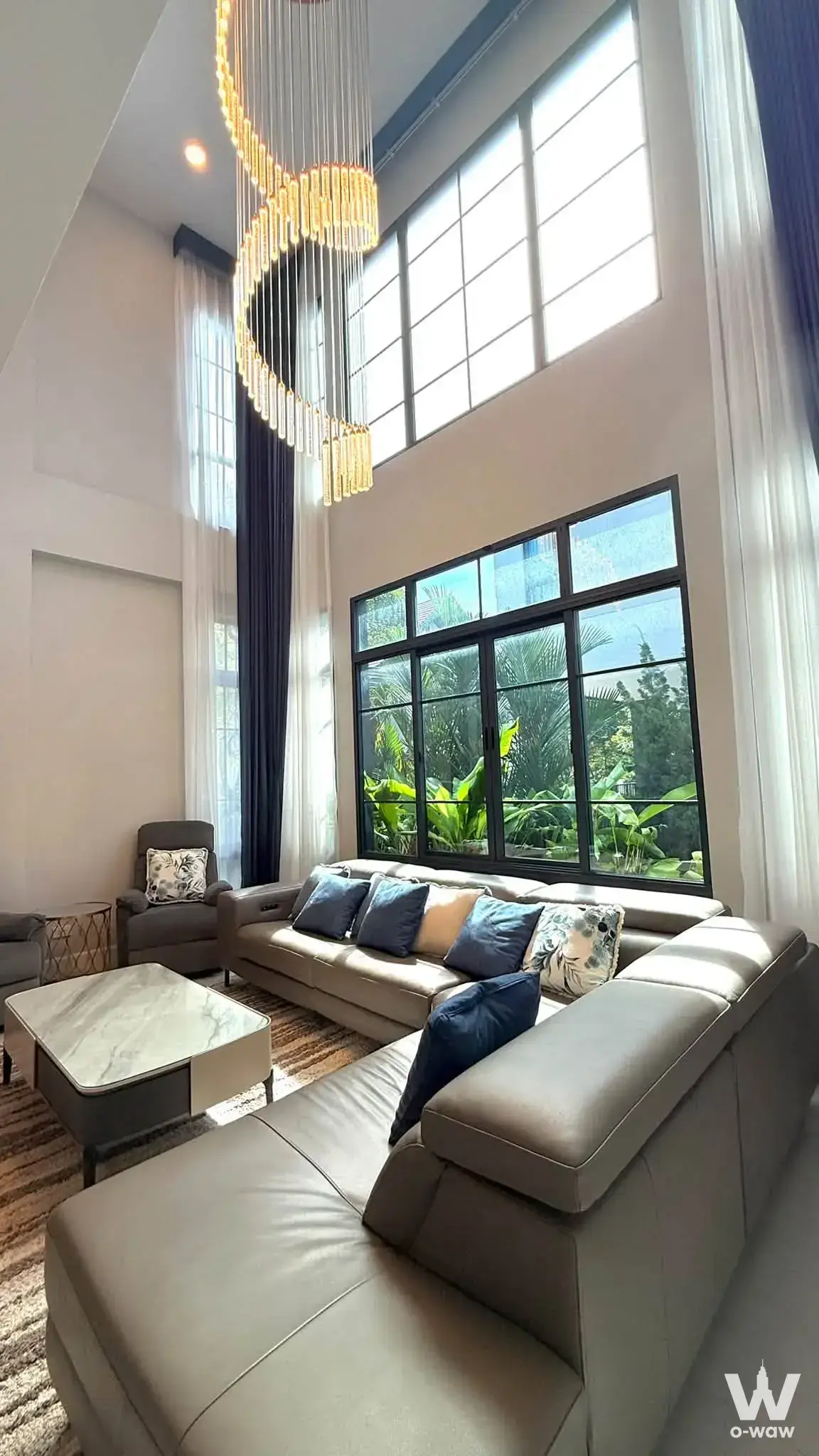 Double-height living room with gold chandelier and spiral design in The City Bangna 2 5-bed house