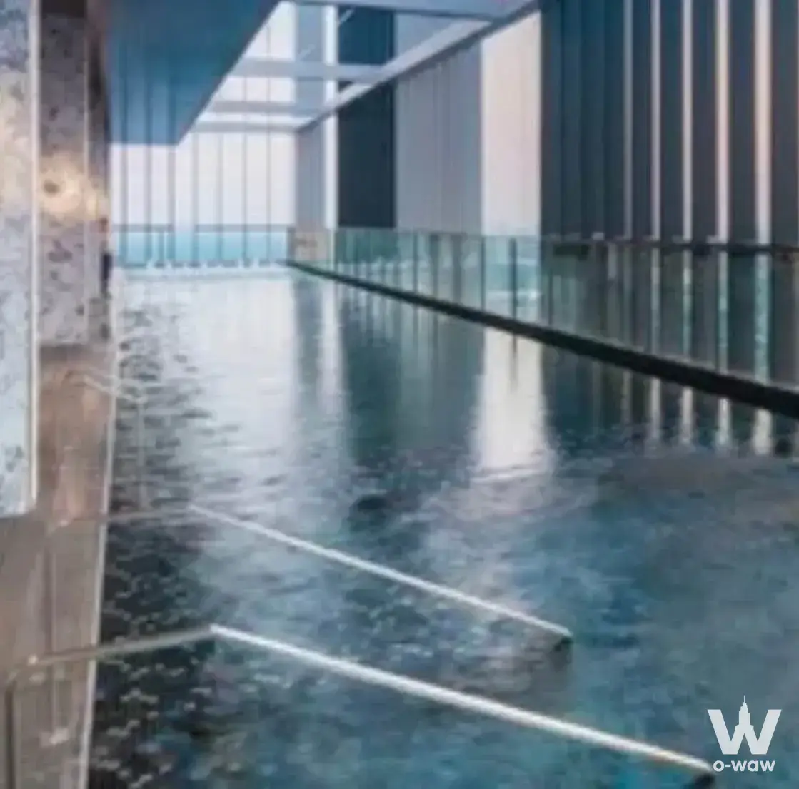 Long lap pool with dark blue mosaic tile and glass barrier in a 1-bed condo at Park Origin Phrom Phong