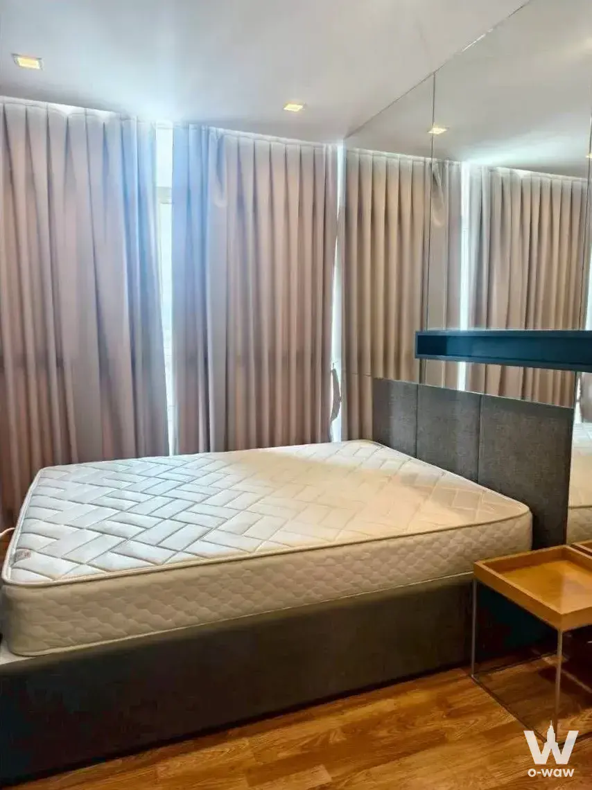 Minimalist bedroom in The Coast Bangkok with mirror wall and warm wood flooring