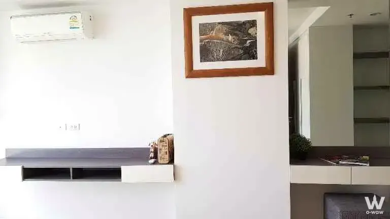 1-bed condo for sale in 15 Sukhumvit Residences featuring minimalist white walls and dark grey desk