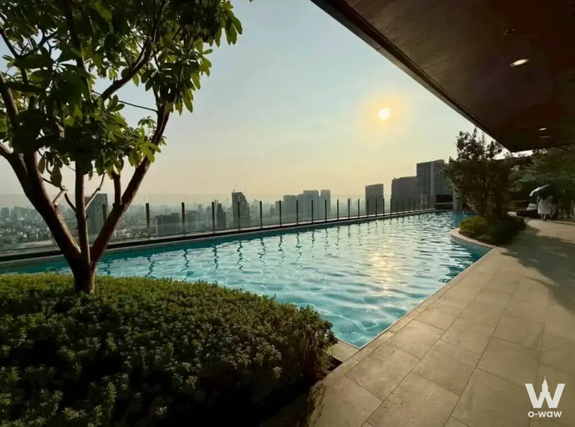 Rooftop infinity pool with turquoise water and hazy city skyline views at The Line Vibe 1-bed condo