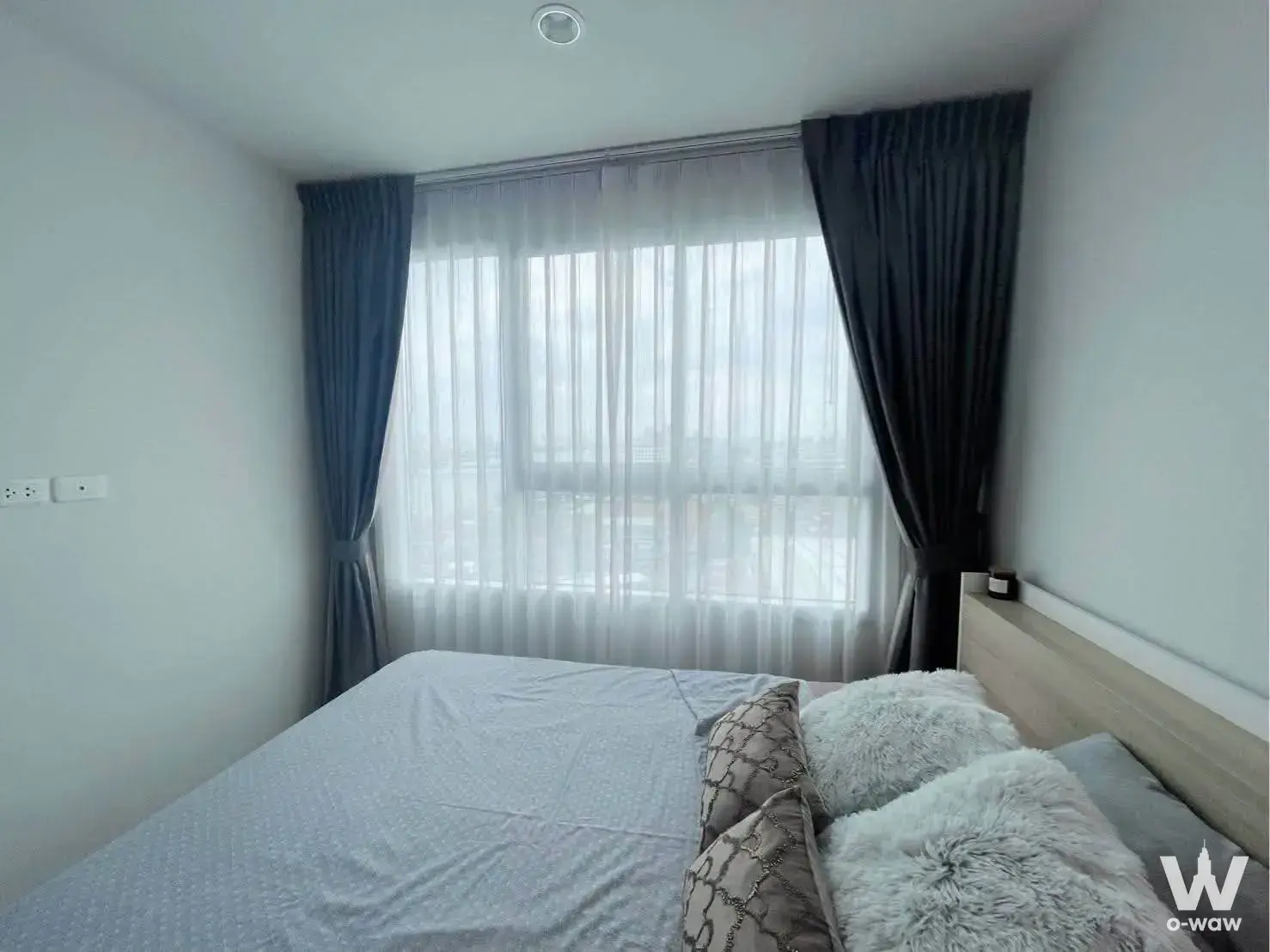 Modern bedroom with grey bedding and blackout curtains in Ideo Charan 70 Riverview 1-bed condo for rent