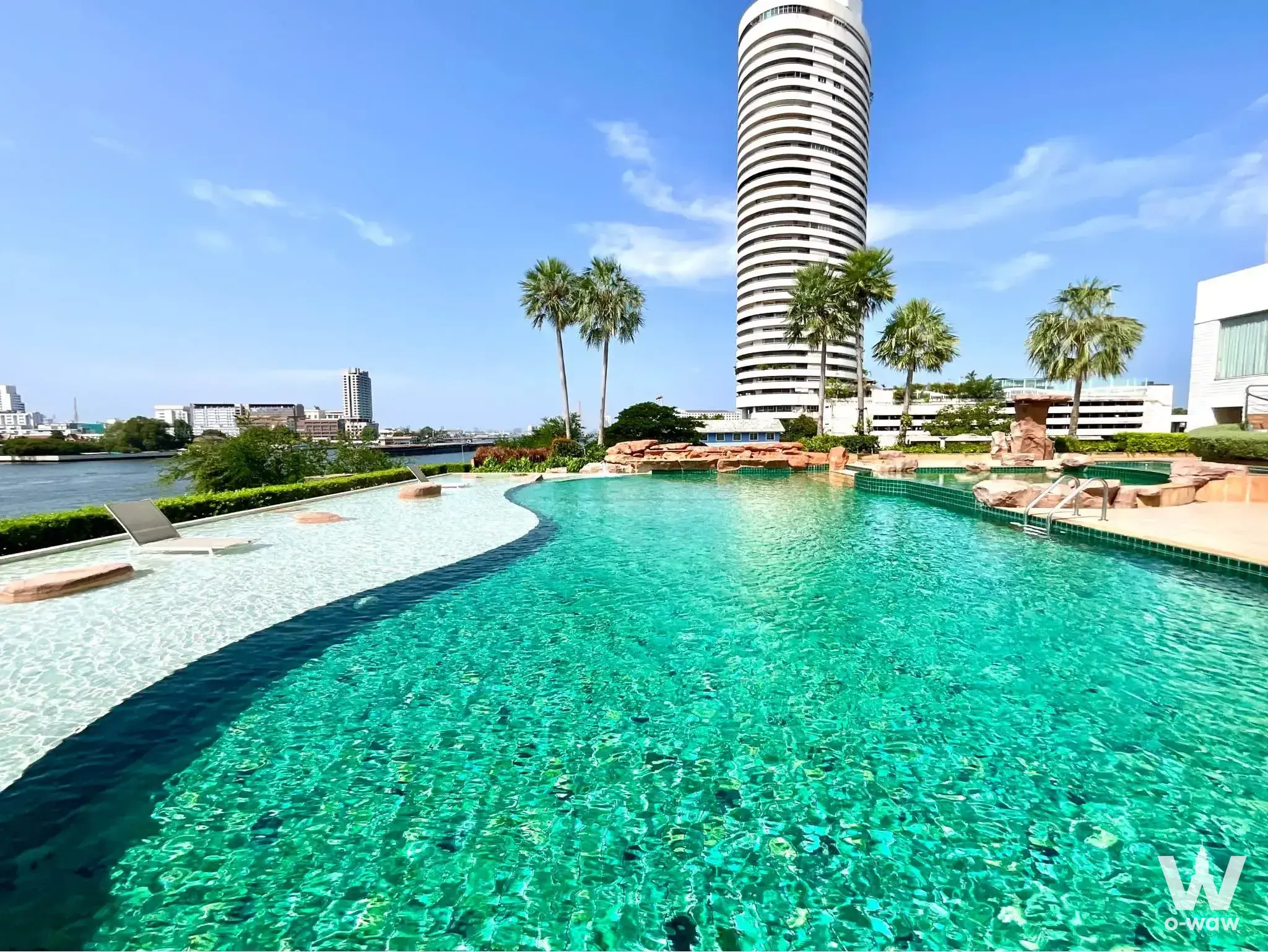 Infinity pool at My Resort @ River condo amenity with turquoise water and palm trees overlooking the city skyline