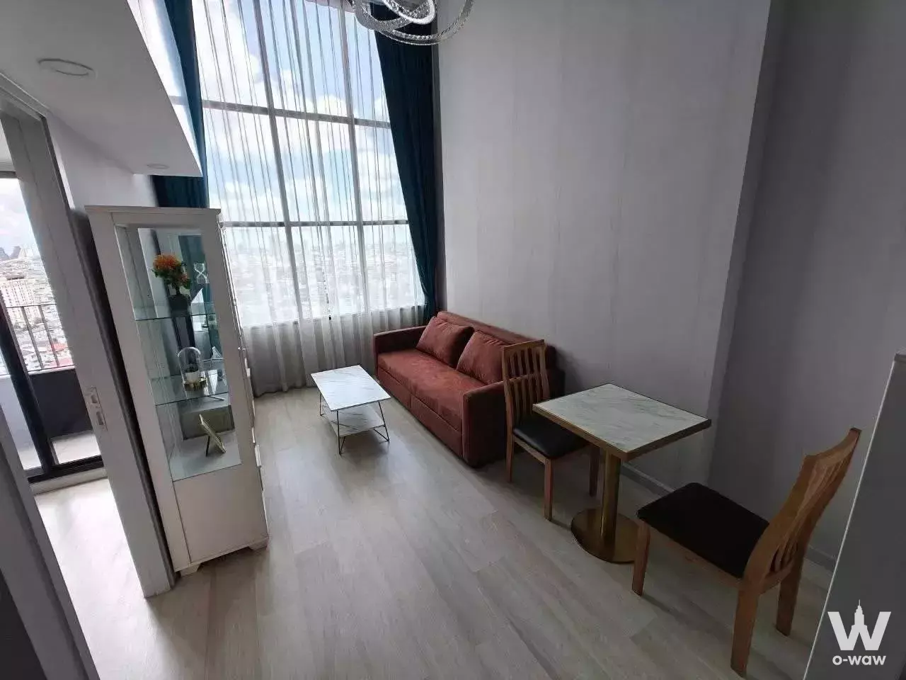 Living room with rust sofa and marble table overlooking the skyline in KnightsBridge Prime Sathon
