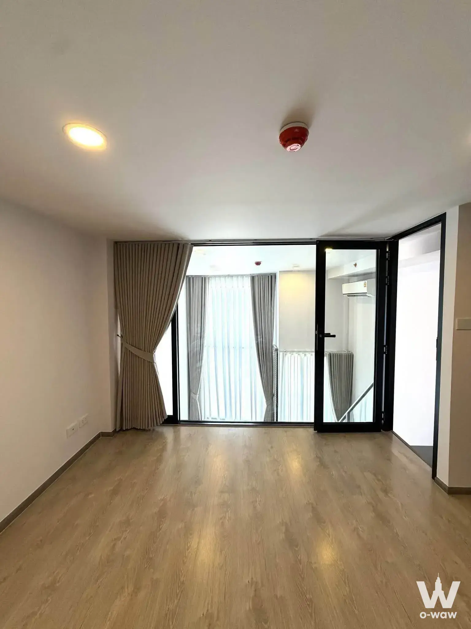 Bright 1-bed condo living room in SOHO Bangkok Ratchada with light wood flooring and balcony access
