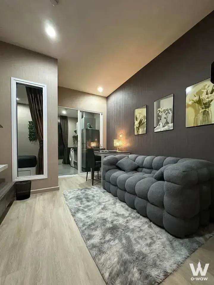 Contemporary living room in Centric Ratchada condo with grey bubble sofa, floral art prints, and dining nook