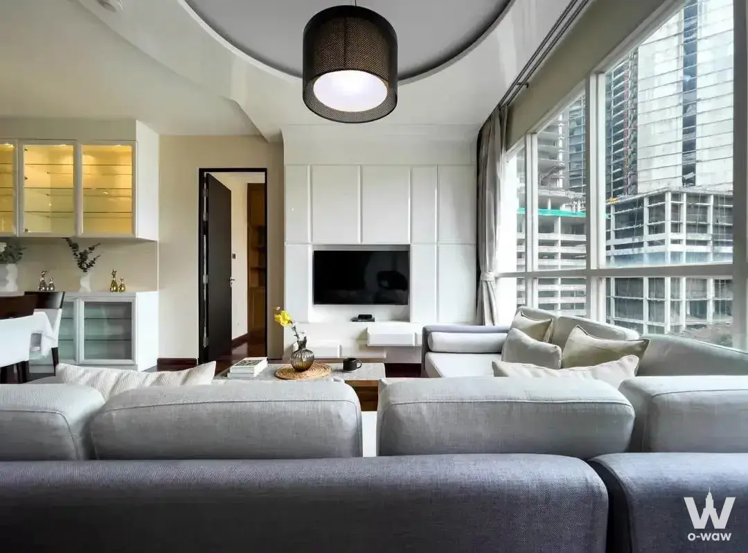 Spacious living room with grey sectional sofa and floor-to-ceiling windows at The Address Chidlom