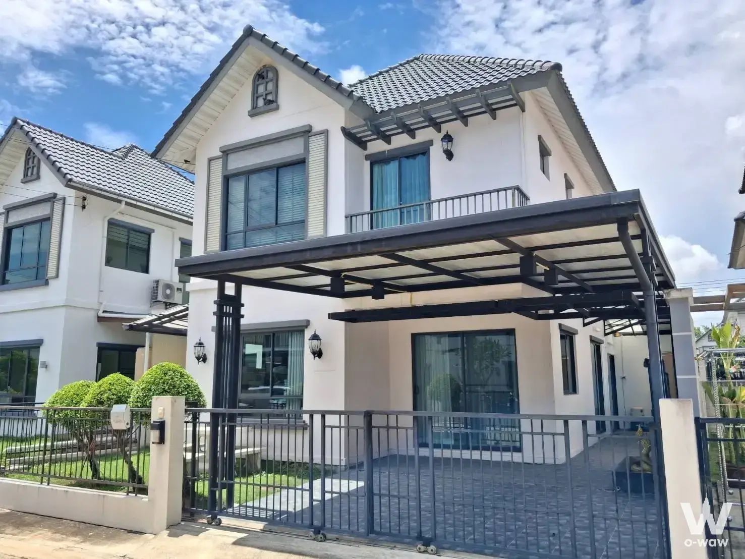2-story detached house exterior with dark grey roof, balcony, and manicured lawn