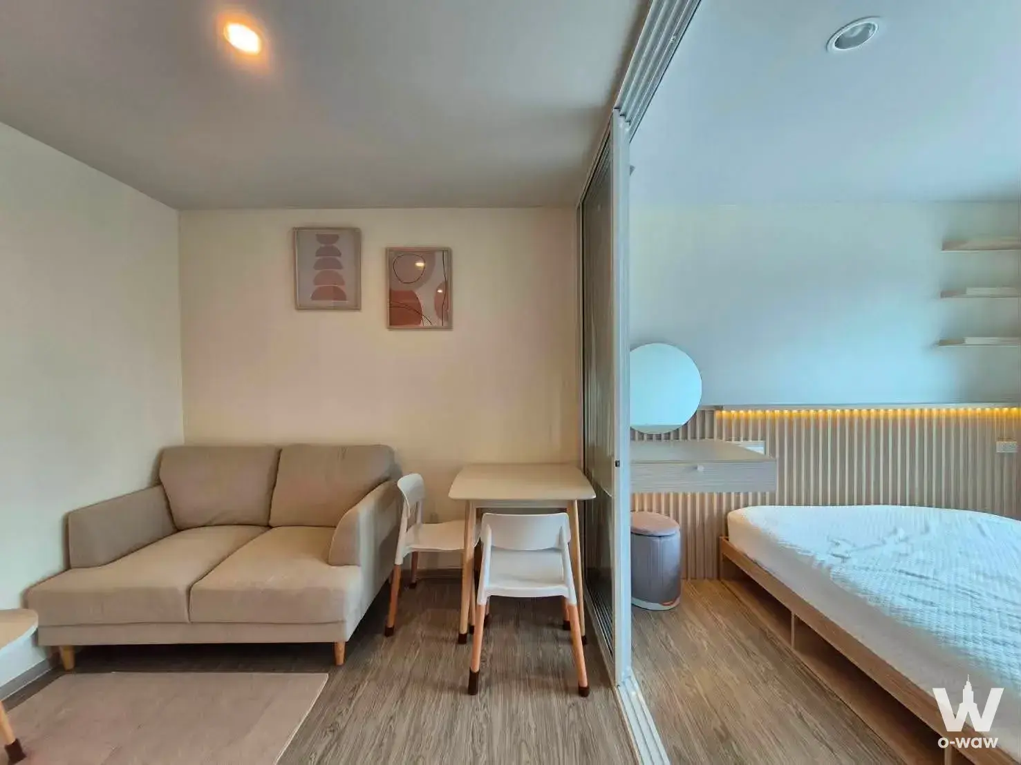 Open-plan studio living area with beige sofa and dining set in a 1-bed condo for rent at Regent Home Bangna