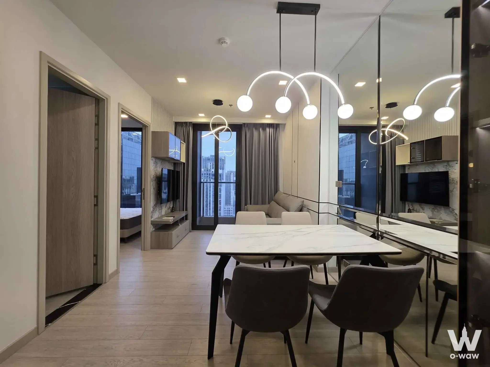 Dining area in One9Five Asoke with marble table, neon pendant light, and mirrored wall