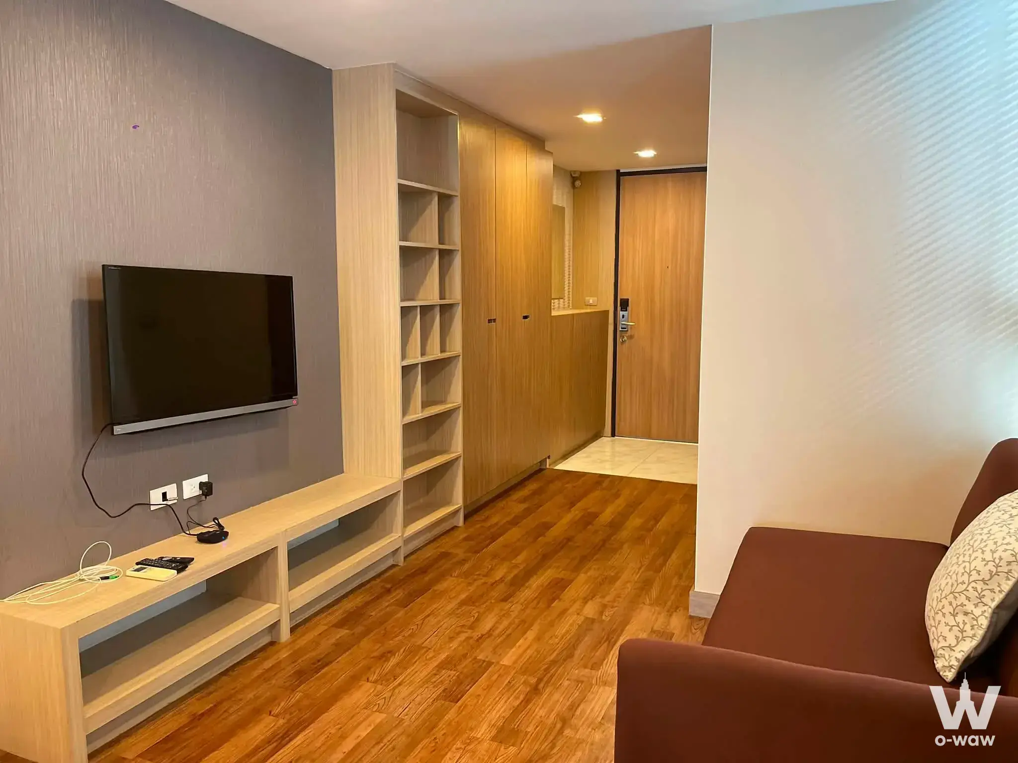 Modern living room in Qube Suites Sukhumvit 46 with dark grey accent wall and wood console