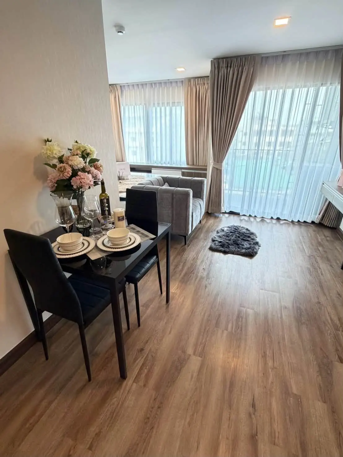 Staged dining-living area in SUN CITY 1-bed condo sale with black table and city view
