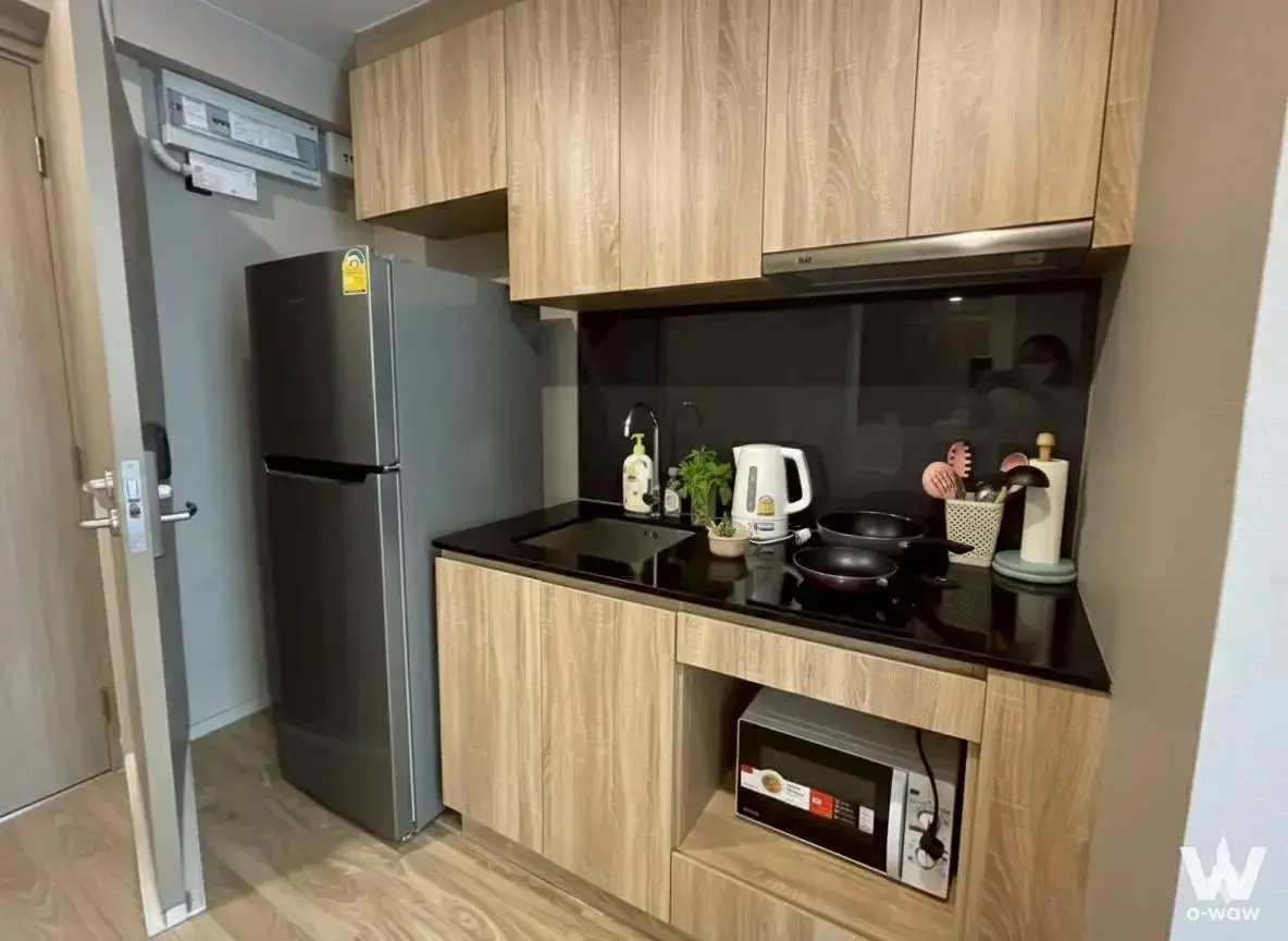 Compact kitchenette in Blossom Condo Sathon-Charoen Rat featuring light wood cabinetry