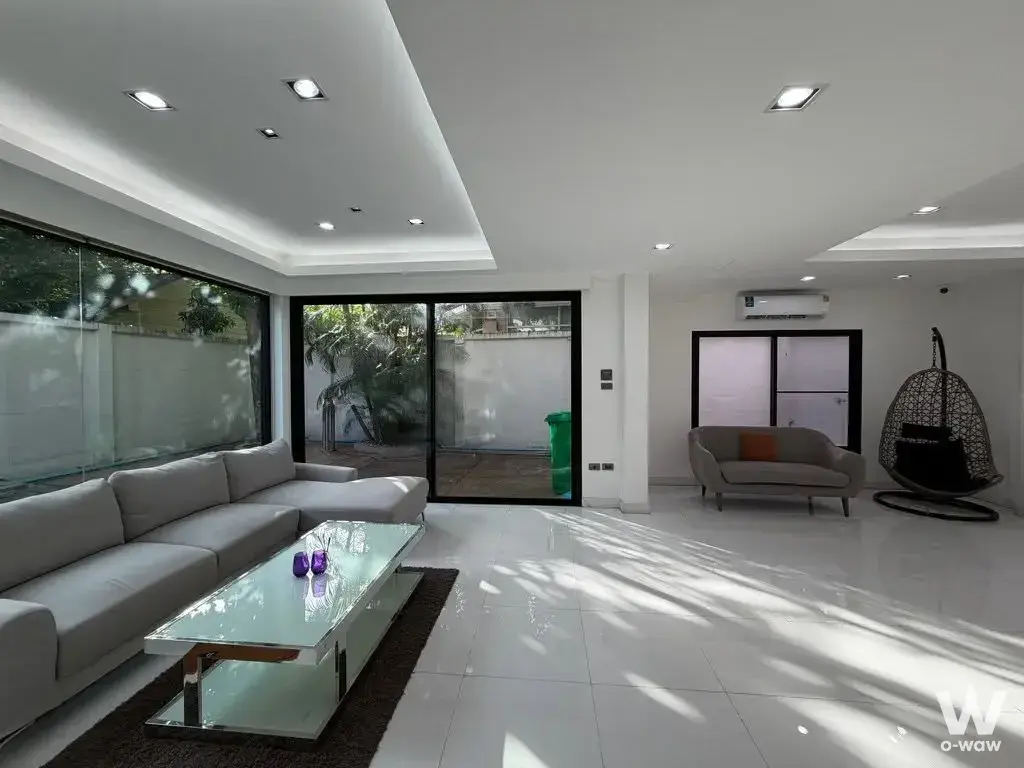 Modern living room with L-shaped sofa and hanging egg chair in JC Tower condo