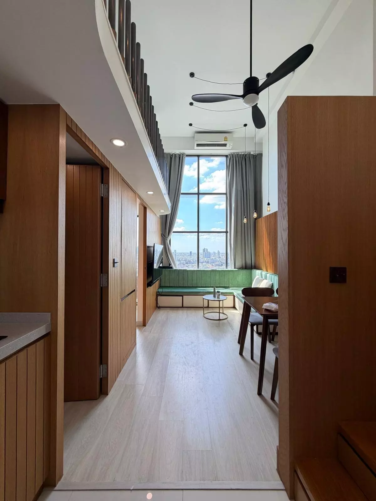 Duplex loft living area in KnightsBridge Prime Sathon for sale with green banquette and city skyline view