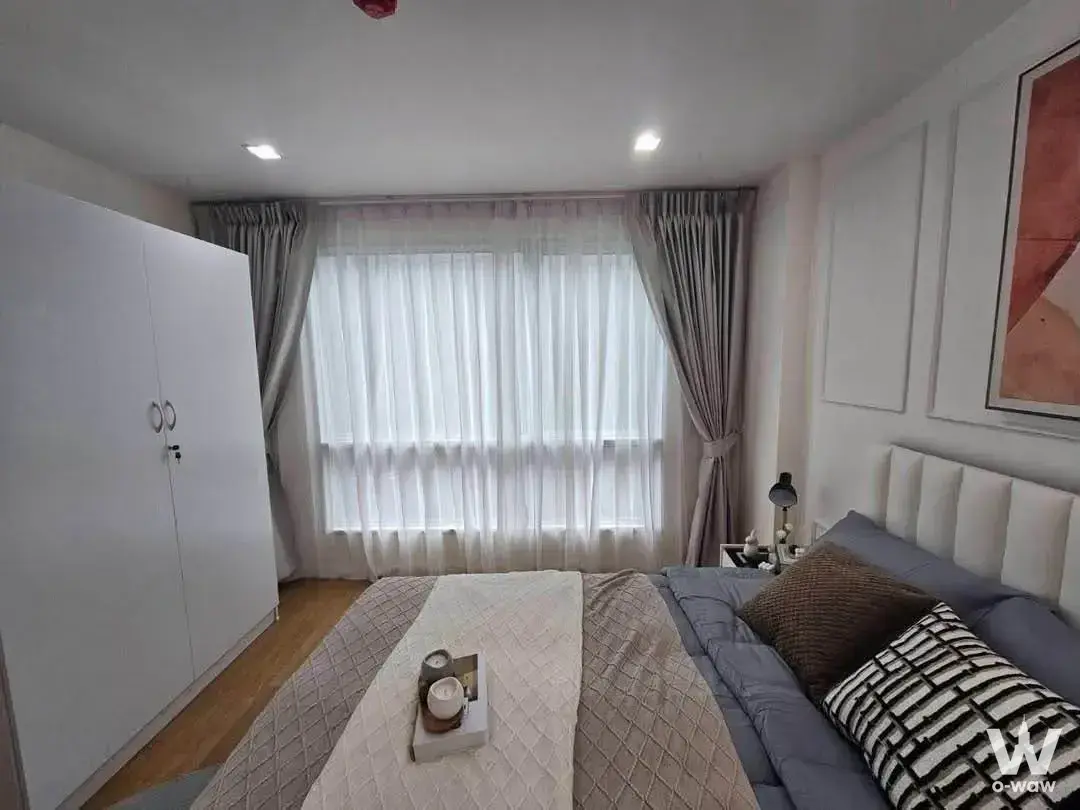 Master bedroom in a 1-bed condo for rent at Casa Condo Ratchada-Thapra has a queen bed and large curtained window