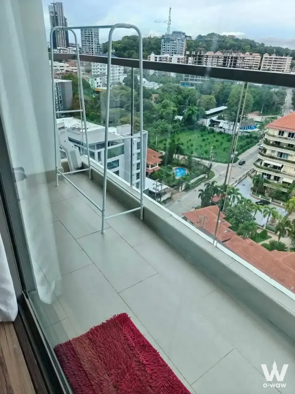 High-rise balcony at The Peak Towers for sale with city park view, pool, and drying rack