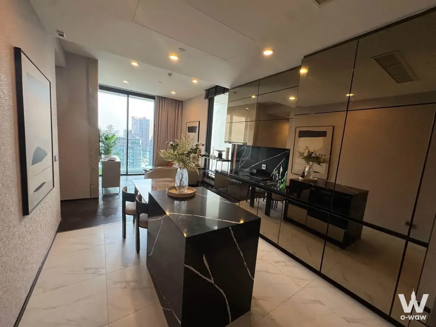 Luxury open-plan condo kitchen with black marble island and mirrored cabinetry at THE ESSE Sukhumvit 36