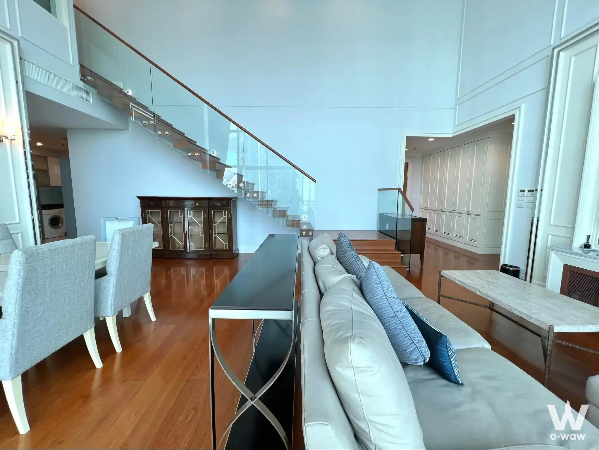 Double-height living room with marble coffee table and hardwood floors in Bright Sukhumvit 24