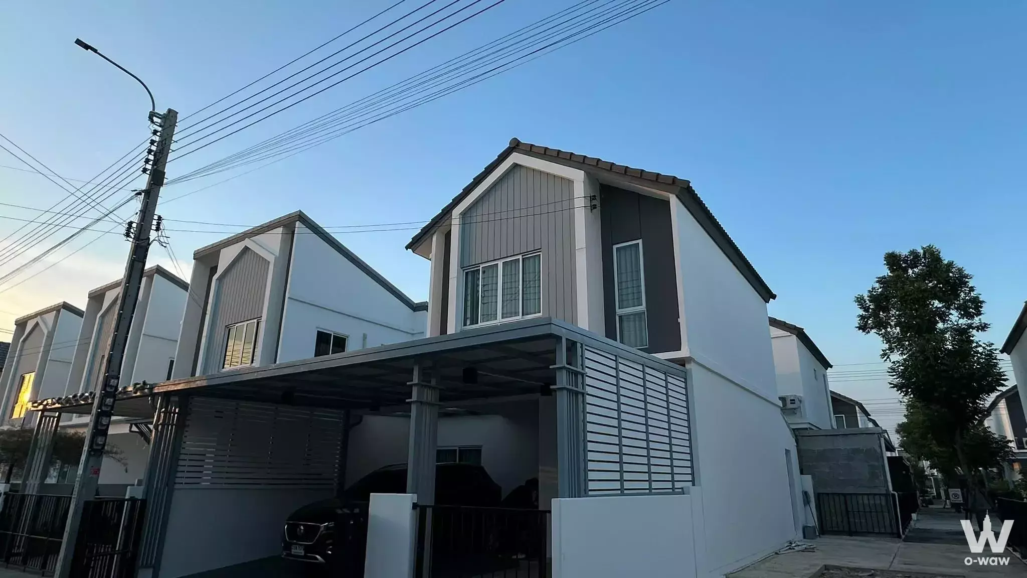 Two-story townhouse exterior at The Connect 56 with white stucco walls, grey metal siding, and a covered carport