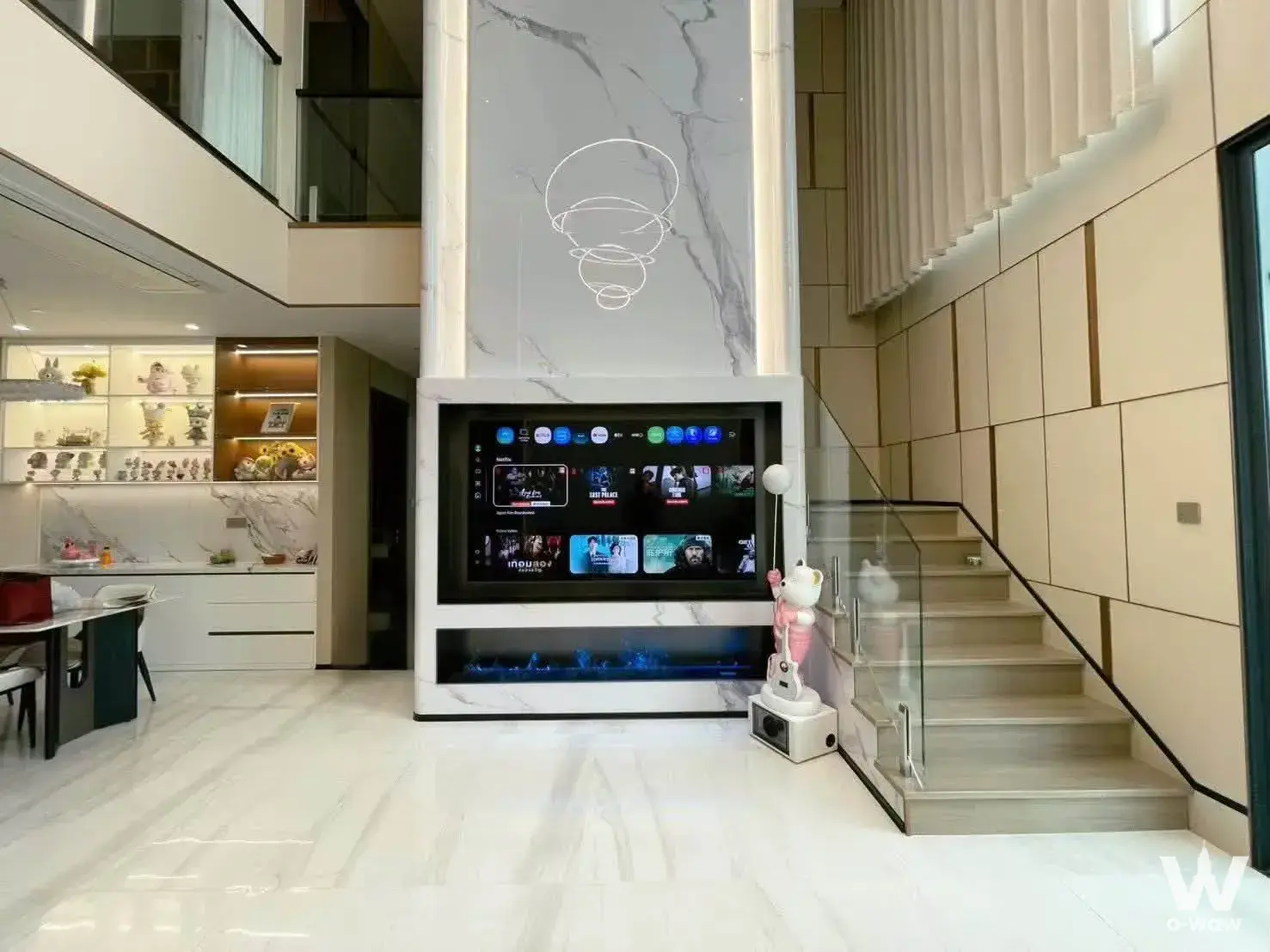 Double-height living room in Supalai Icon Sathorn featuring marble walls, electric fireplace, and glass staircase