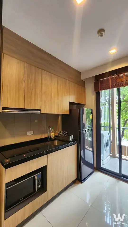Compact kitchen in HASU HAUS 1-bed condo featuring black granite counters and stainless appliances