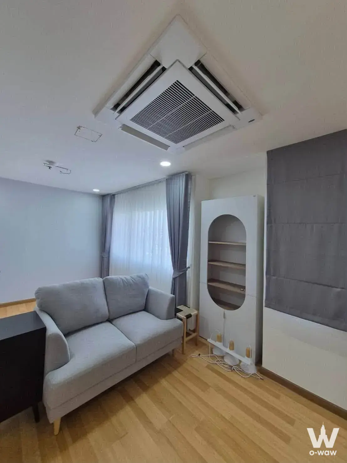 Minimalist living room with grey sofa and arched shelving in P. Thana Tower condo