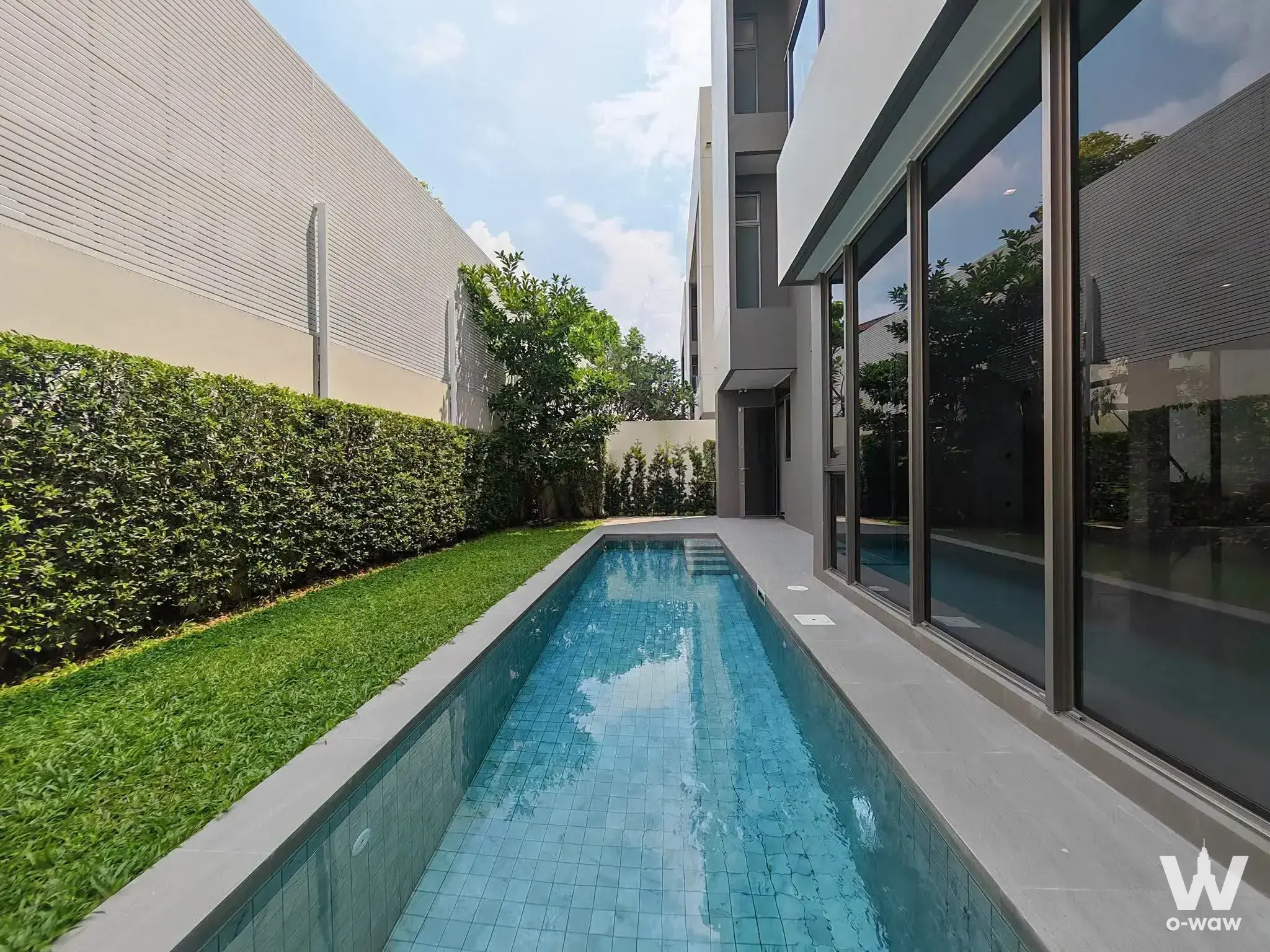 Private pool with blue mosaic tiles and manicured grass at this 4-bed house for sale in Providence Lane Kaset Nawamin