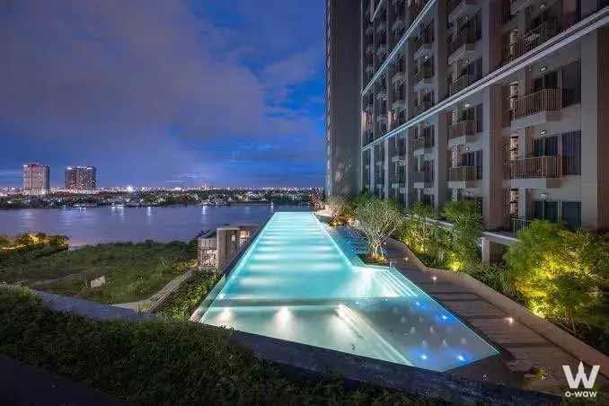 Infinity pool with cyan LED lighting at The Politan Aqua, featuring river views and twilight skyline