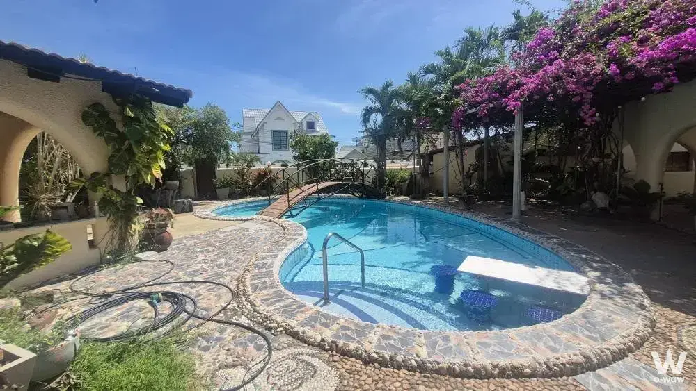 Kidney-shaped pool backyard in Natheekarn Park View house with bougainvillea and bridge