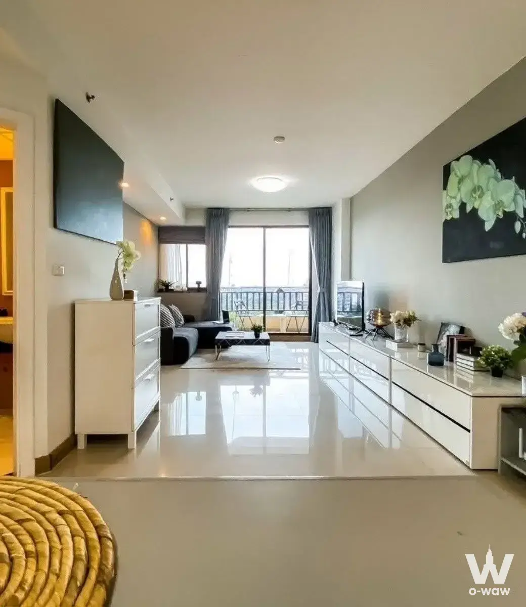 Living room with grey sofa and balcony access in 2-bed condo for sale at Supalai Oriental Place Sathorn-Suanplu