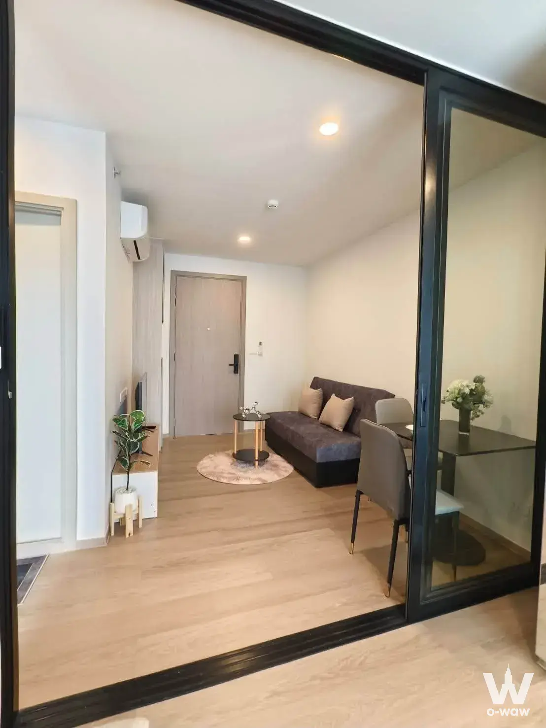 Living-dining room in a 1-bed condo for rent at Origin Play Bangkhunnon Triple Station with a charcoal sofa and a glass