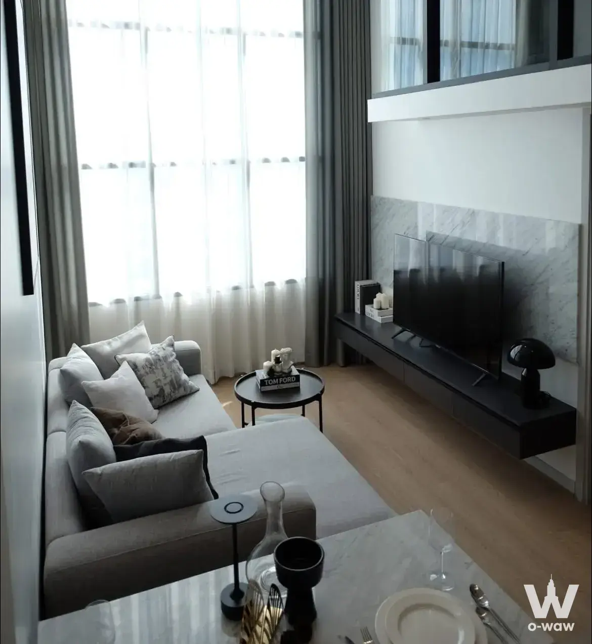Bright living room in a 2-bed KnightsBridge Prime Sathon rental shows a grey sectional and marble TV wall