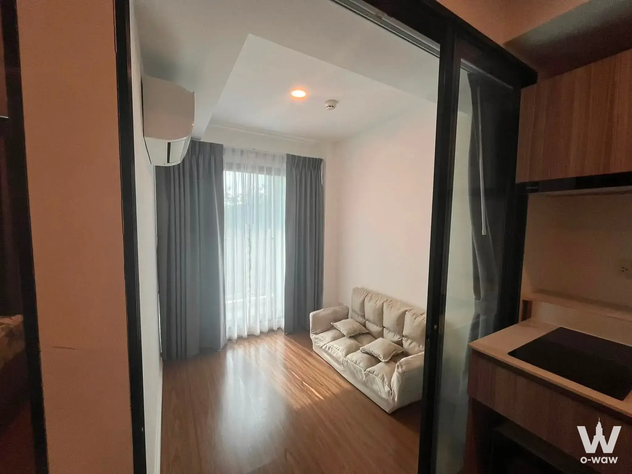 Furnished living area with beige sofa and wood-look flooring in a 2-bed condo for rent in The Origin Phahol-Saphanmai