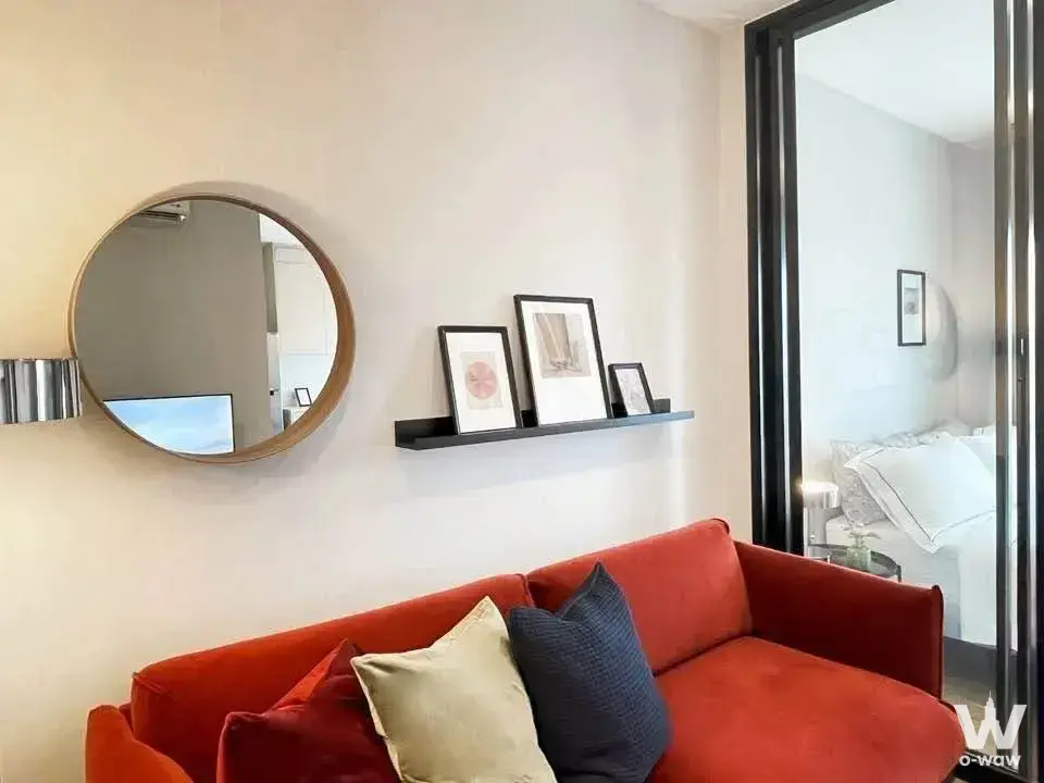 Burnt-orange sofa and large mirror in a furnished 1-bed condo for rent at Metris Rama 9-Ramkumhang