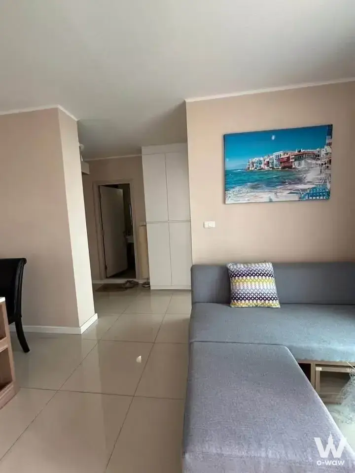 DCondo Nim 2-bed condo living room featuring grey sectional sofa and blue beach scene artwork