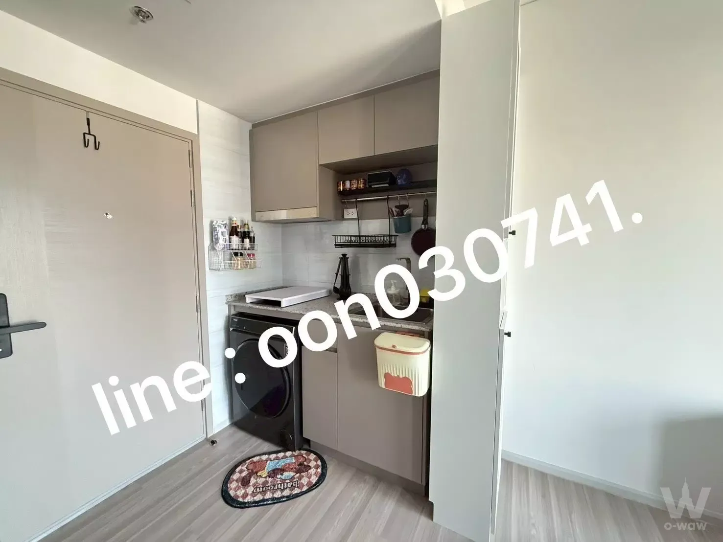 Compact L-shaped kitchenette with grey cabinets and a washing machine in this QUINTARA MHy'DEN Pho Nimit 1-bed rental