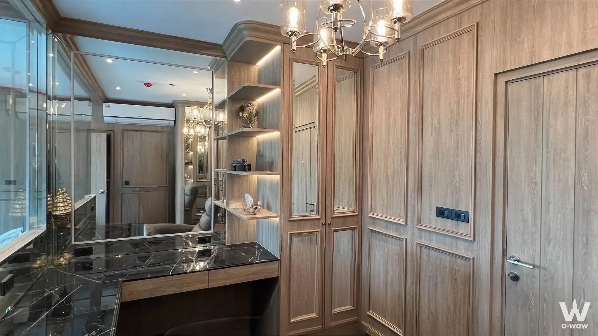 Luxury walk-in closet with oak paneling, black marble vanity, and LED lighting in a 1-bed condo for sale at The Tree Rio