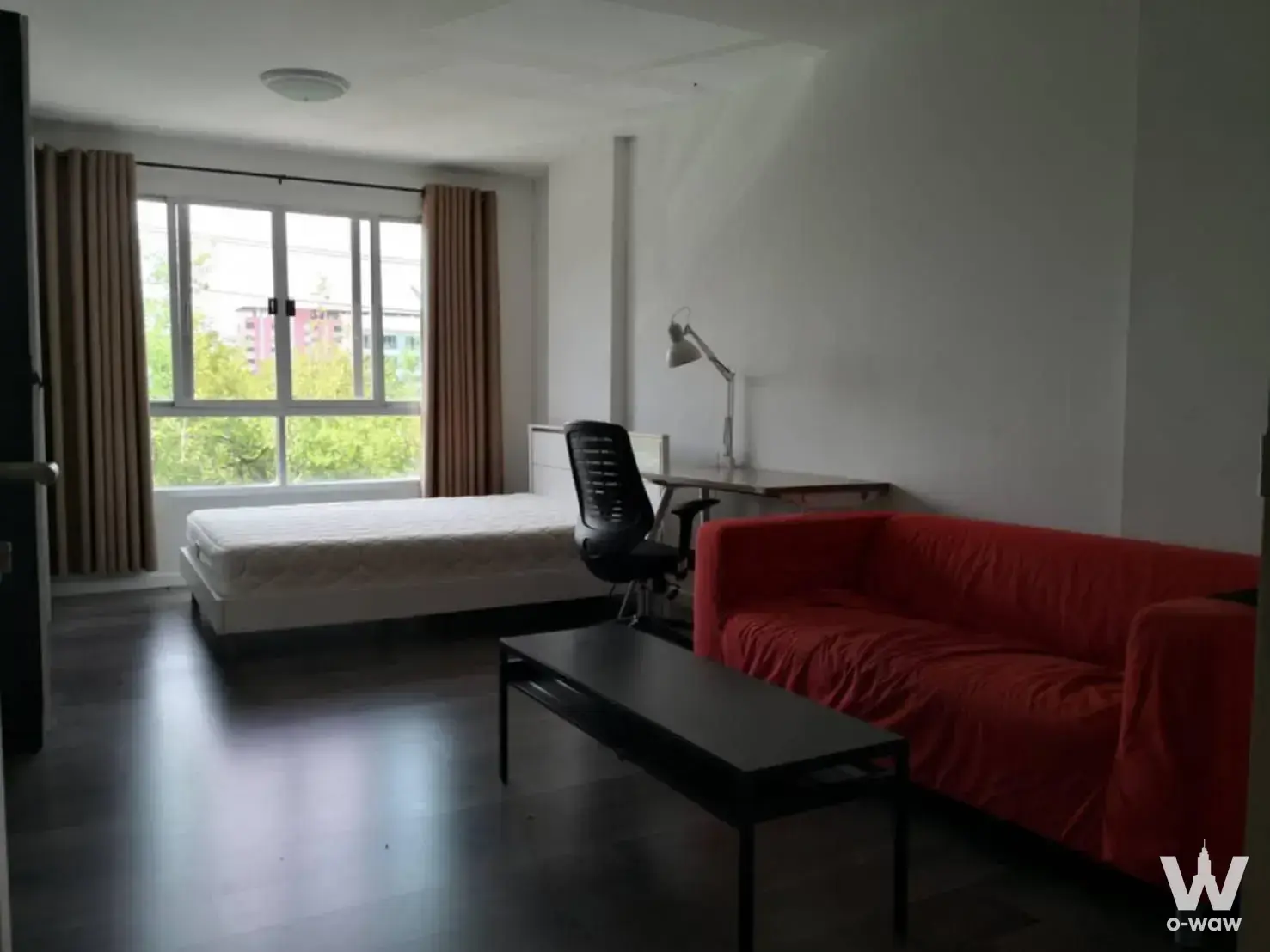 Studio condo for sale in dcondo Campus Resort Bangna featuring red sofa and queen bed under window