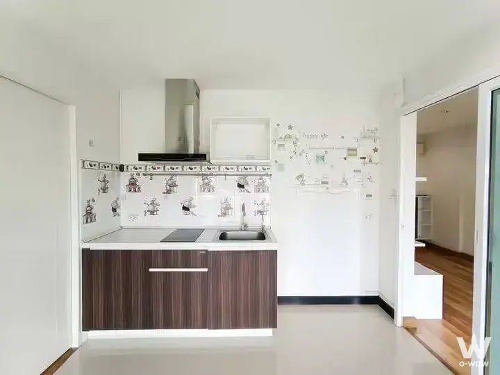 Functional kitchen with dark cabinetry, white countertop, and playful robot-themed backsplash tiles in Apool Condo