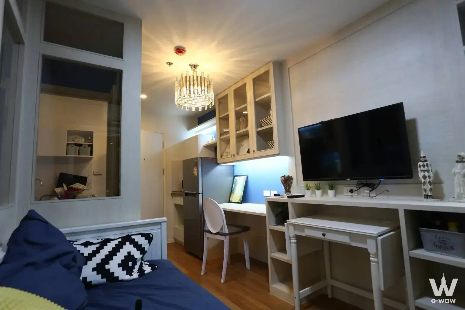 Studio in The Selected Kaset-Ngamwongwan rental condo with navy bedding, glass kitchen partition and LED-lit cabinets