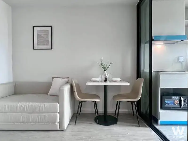 The living area has a grey sofa and a glass kitchen partition in this Atmoz Oasis Onnut rental