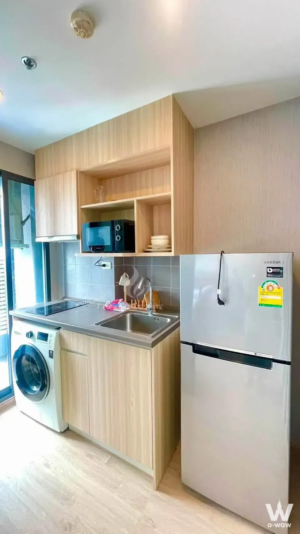 Compact kitchenette with oak cabinets and induction cooktop in an Ideo O2 1-bed unit