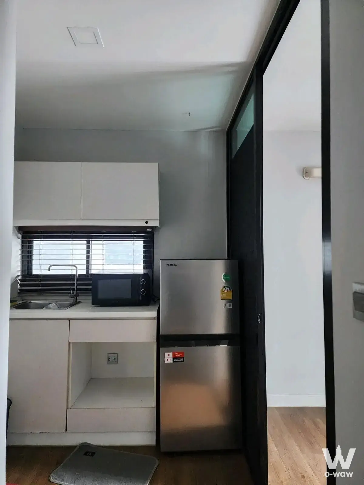 White kitchenette with stainless appliances in this 2-bed condo at ESTA Bliss Condo