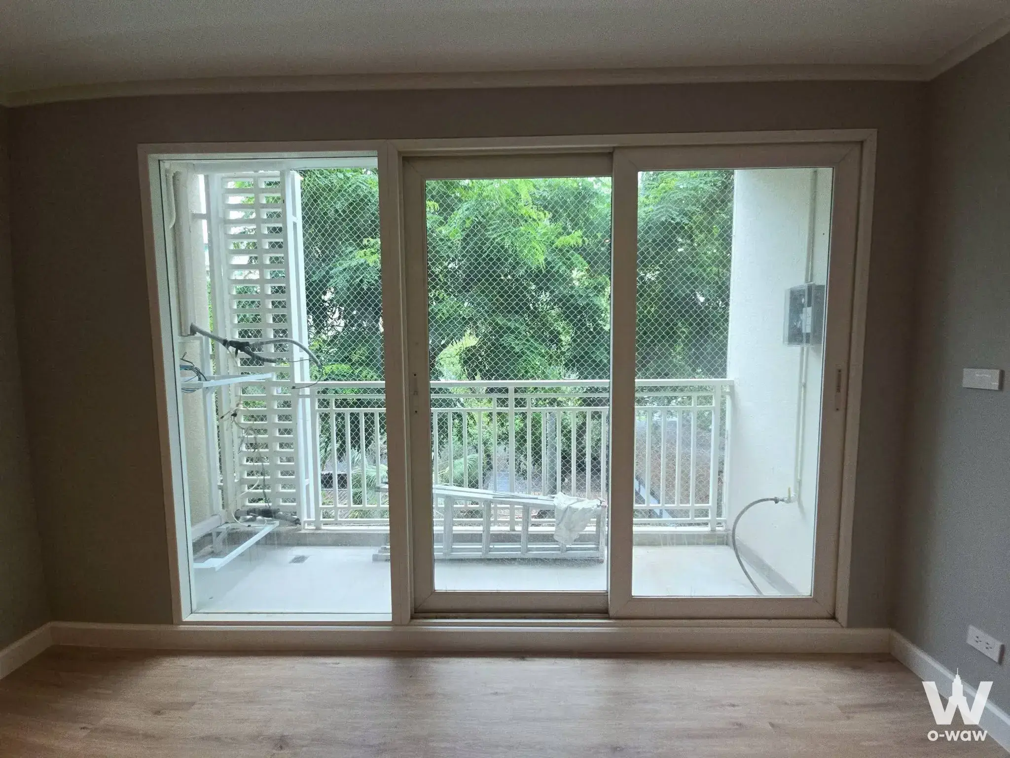 Empty room with balcony access for sale in Baan Siriyenakat showing green foliage view