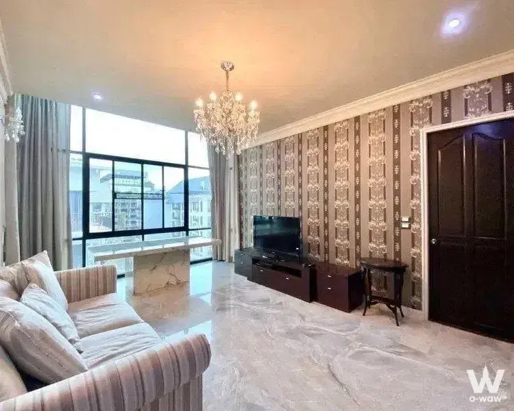 Beige striped sofa and crystal chandelier in the living room of a 2-bed condo for rent at Amanta Ratchada