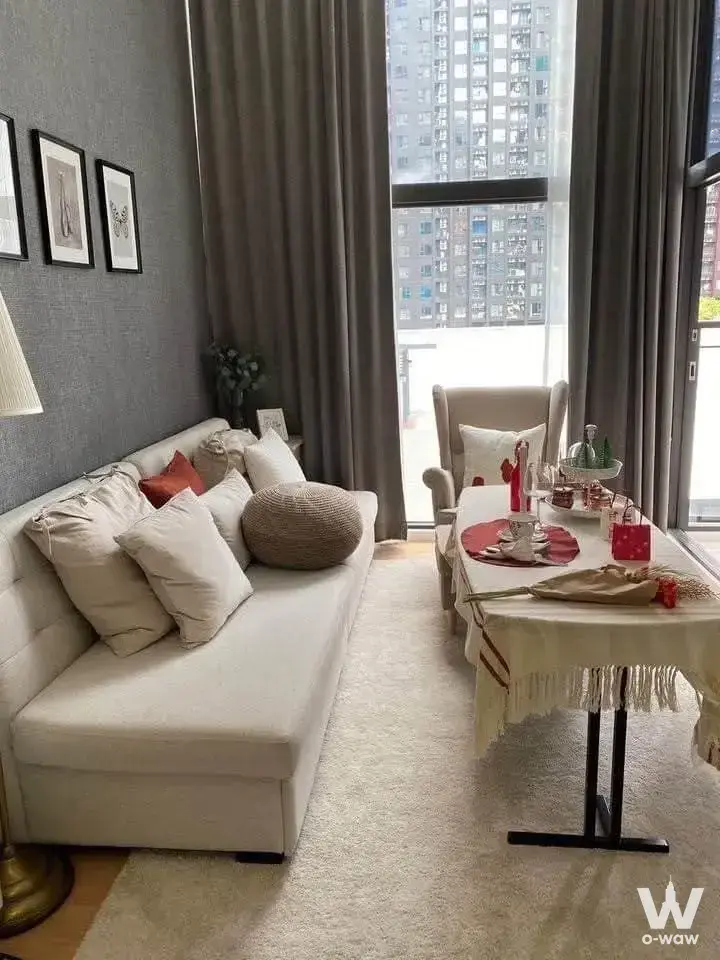 Living room in a 1-bed condo for rent at Chewathai Residence Asoke featuring a sofa, city view, and red accents